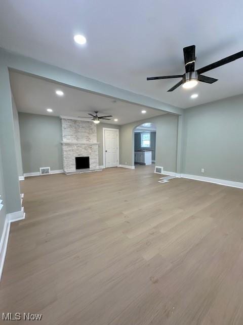 unfurnished living room featuring a fireplace, light hardwood / wood-style floors, and ceiling fan