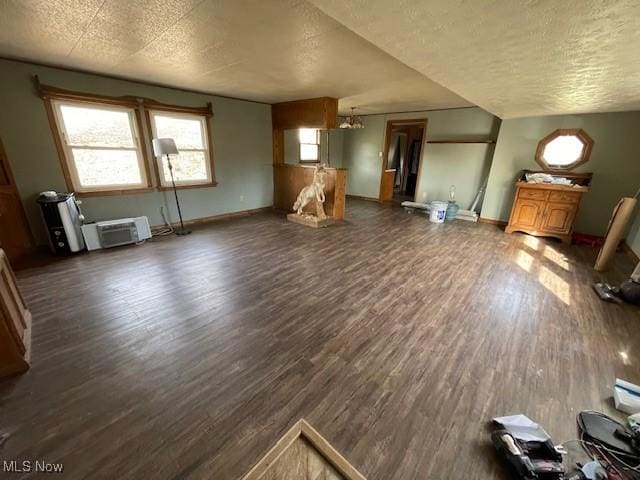 unfurnished living room featuring dark wood-type flooring, a wall mounted AC, and a textured ceiling