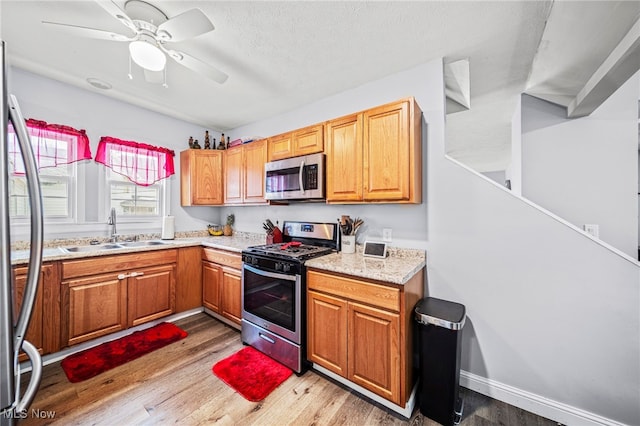 kitchen with sink, ceiling fan, stainless steel appliances, a textured ceiling, and light hardwood / wood-style flooring