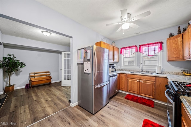 kitchen with wood-type flooring, appliances with stainless steel finishes, sink, and a textured ceiling