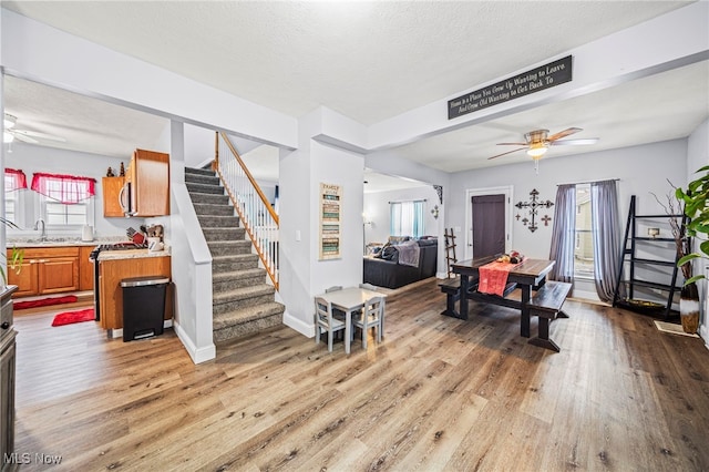 living room with ceiling fan, a wealth of natural light, sink, and light wood-type flooring