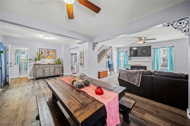 dining space featuring ceiling fan, a brick fireplace, and light wood-type flooring