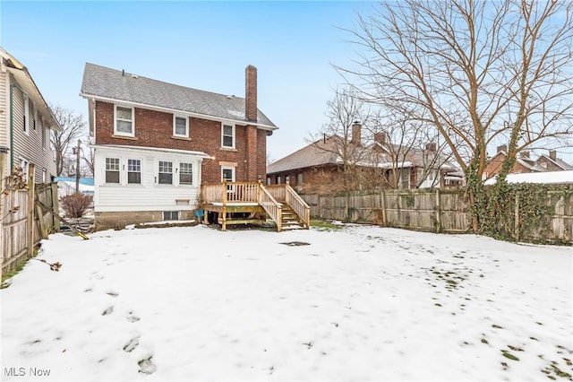 snow covered rear of property with a wooden deck