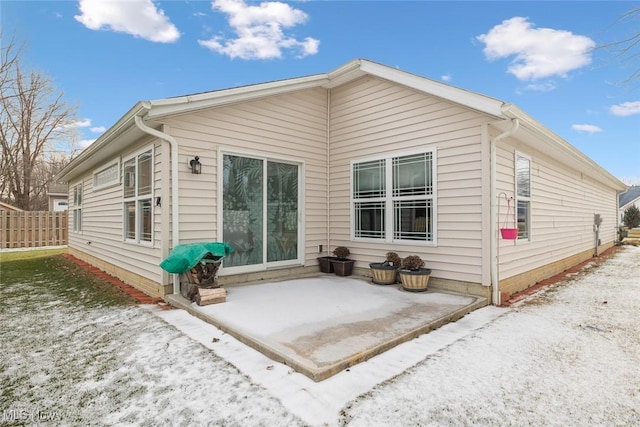 snow covered rear of property featuring a patio area