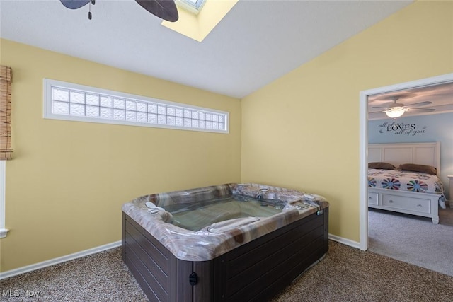 bedroom featuring ceiling fan, dark carpet, and vaulted ceiling with skylight