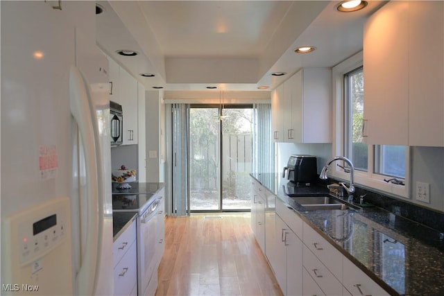 kitchen with pendant lighting, white appliances, dark stone counters, and white cabinets