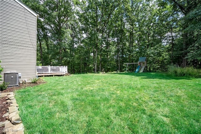 view of yard featuring a wooden deck, a playground, and central air condition unit