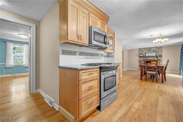 kitchen with appliances with stainless steel finishes, decorative backsplash, light brown cabinets, a textured ceiling, and light hardwood / wood-style flooring