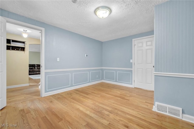 spare room with a textured ceiling and light hardwood / wood-style flooring