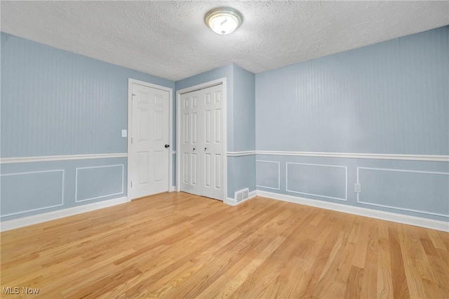 empty room with a textured ceiling and light wood-type flooring