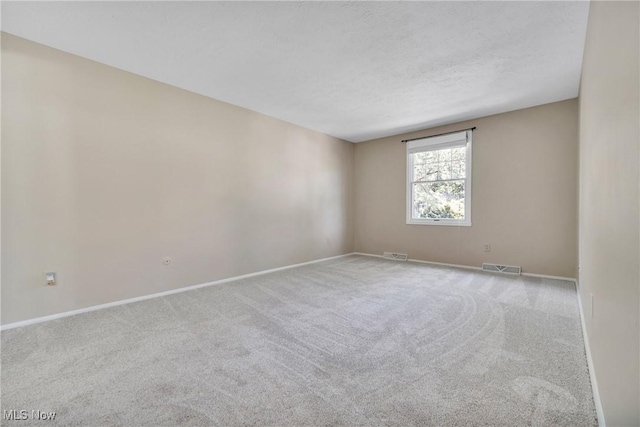 carpeted empty room featuring a textured ceiling