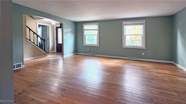 unfurnished room with a textured ceiling and light wood-type flooring