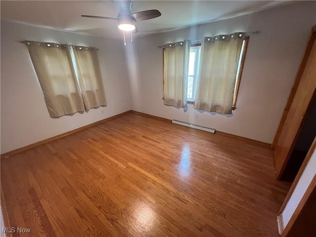 empty room with light wood-style floors, baseboards, ceiling fan, and baseboard heating