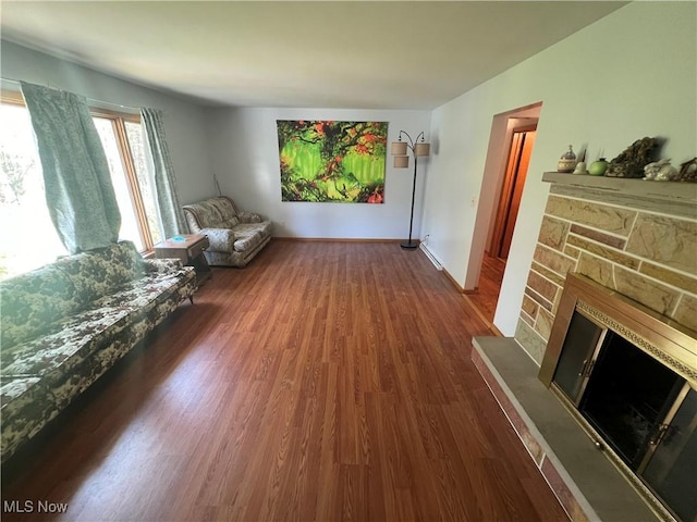 living area with baseboards, dark wood-style flooring, and a fireplace