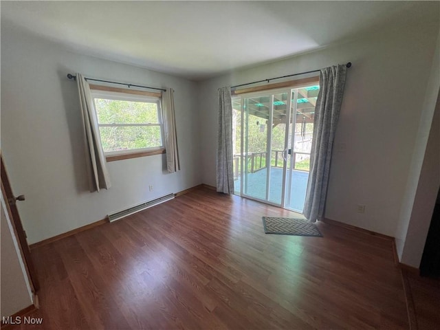 unfurnished room with a baseboard heating unit and dark hardwood / wood-style floors