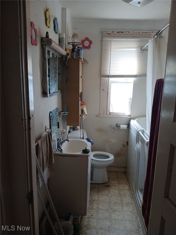 bathroom featuring a shower with curtain, vanity, toilet, and washer and dryer