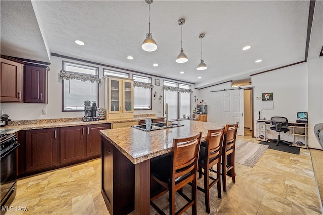 kitchen with sink, a center island, hanging light fixtures, a barn door, and black gas range