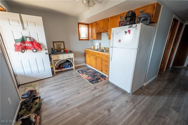 kitchen featuring white fridge, sink, ceiling fan, and light hardwood / wood-style flooring