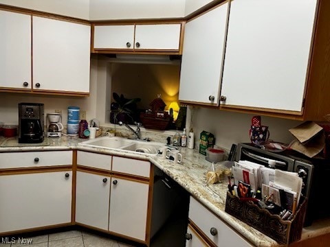 kitchen featuring light tile patterned floors, white cabinets, a sink, light stone countertops, and dishwasher