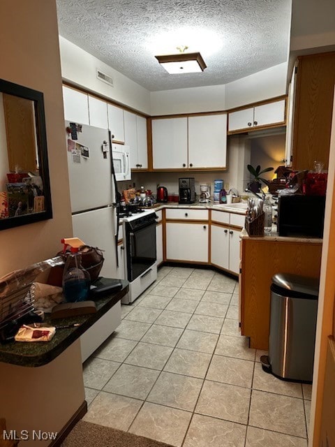 kitchen with light tile patterned floors, visible vents, white cabinets, a textured ceiling, and white appliances