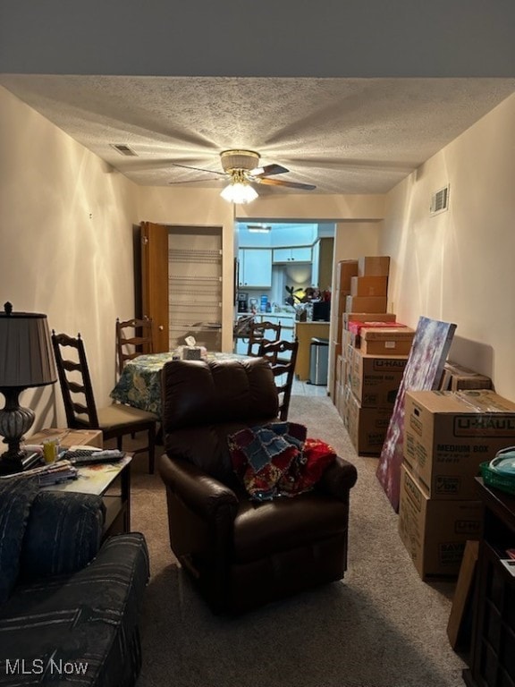 interior space with light carpet, visible vents, a textured ceiling, and a ceiling fan