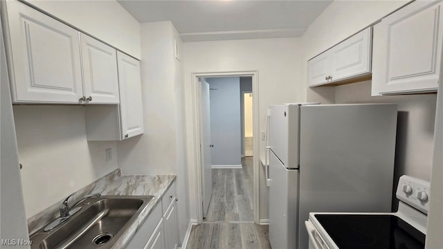 kitchen featuring white appliances, light hardwood / wood-style floors, sink, and white cabinets