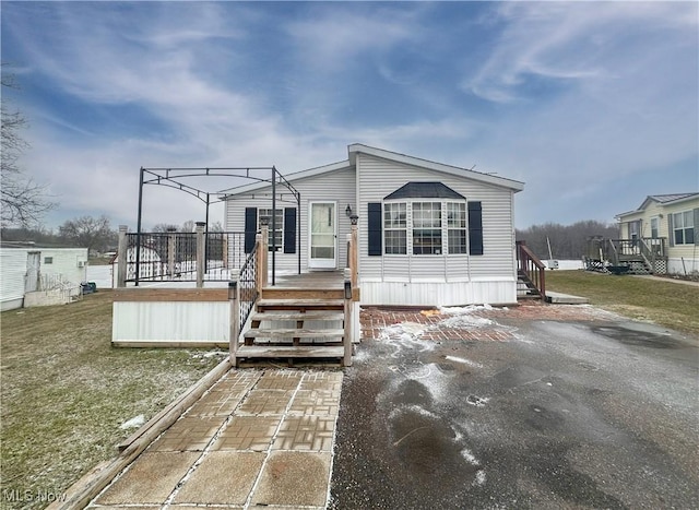 manufactured / mobile home featuring a deck and a front lawn