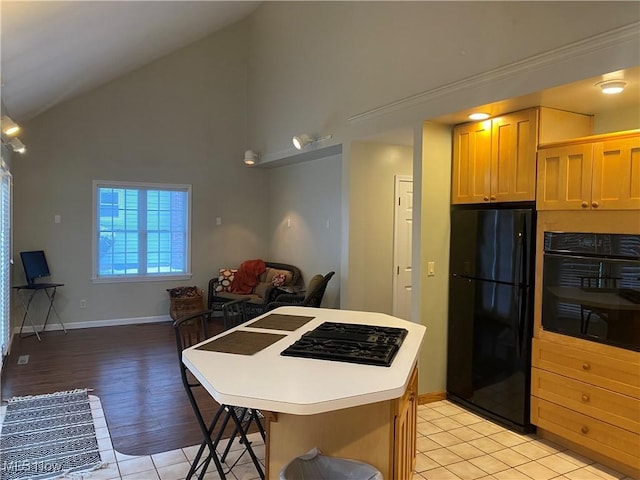 kitchen featuring high vaulted ceiling, light hardwood / wood-style flooring, a kitchen breakfast bar, a kitchen island, and black appliances