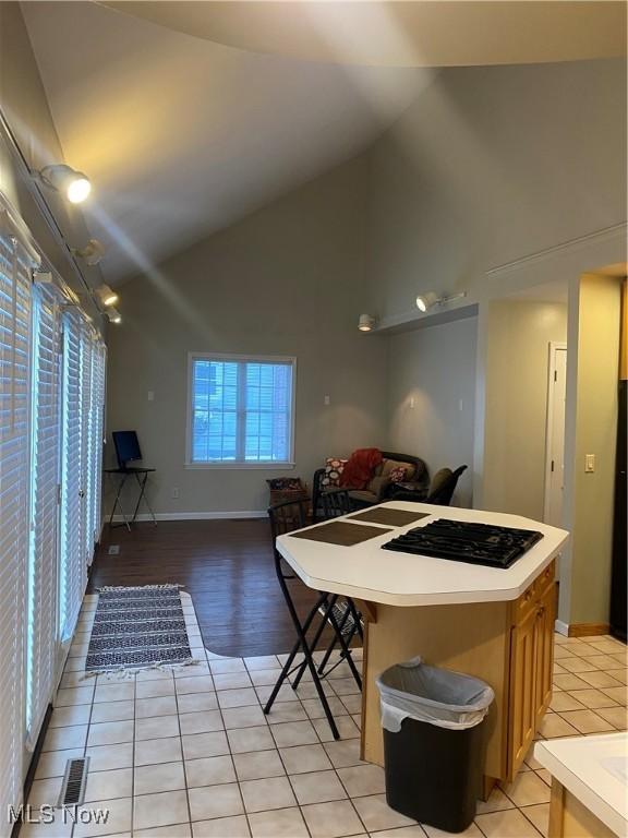 kitchen featuring high vaulted ceiling, light tile patterned flooring, a breakfast bar, and a kitchen island