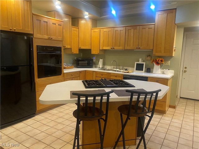 kitchen featuring sink, a center island, light tile patterned floors, a kitchen breakfast bar, and black appliances