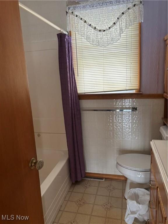 full bathroom with shower / tub combo, vanity, toilet, and tile walls