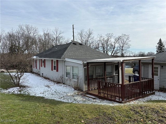 snow covered rear of property featuring a yard and a deck