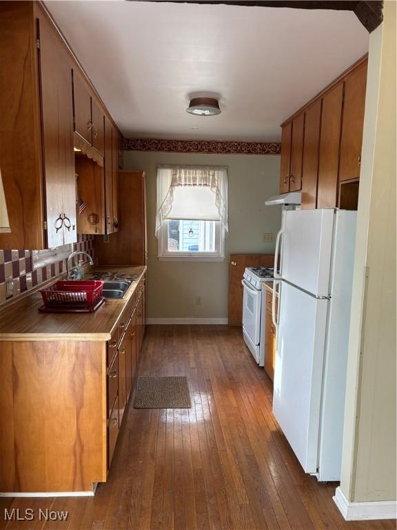 kitchen with dark wood-type flooring, white appliances, and sink