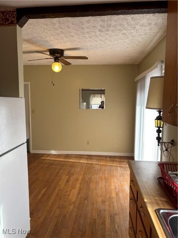 kitchen featuring sink, wooden counters, white refrigerator, hardwood / wood-style flooring, and a textured ceiling