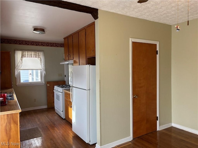 kitchen with white appliances, dark hardwood / wood-style flooring, and a textured ceiling