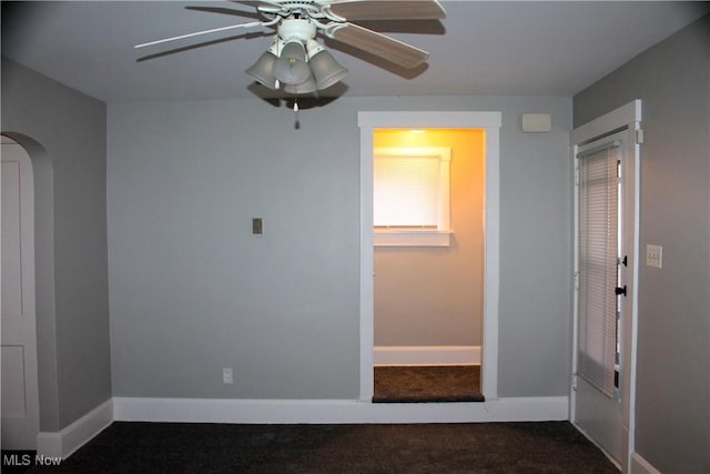 unfurnished room with baseboards, arched walkways, and ceiling fan