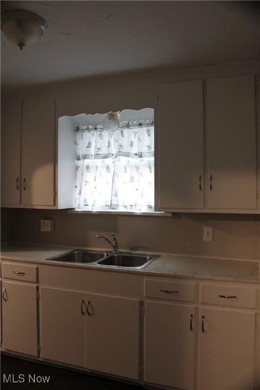 kitchen featuring white cabinetry, light countertops, and a sink