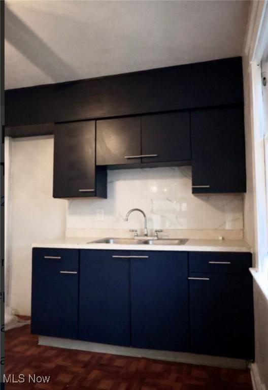 kitchen with tasteful backsplash, sink, dark parquet flooring, and blue cabinets