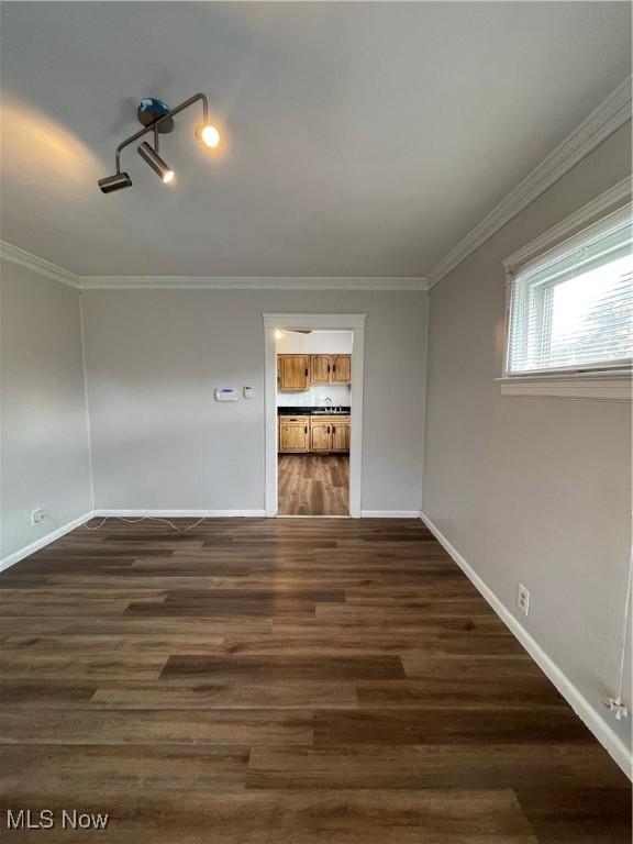 spare room featuring crown molding and dark wood-type flooring