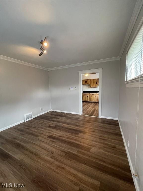 spare room featuring ornamental molding, dark wood-type flooring, and track lighting