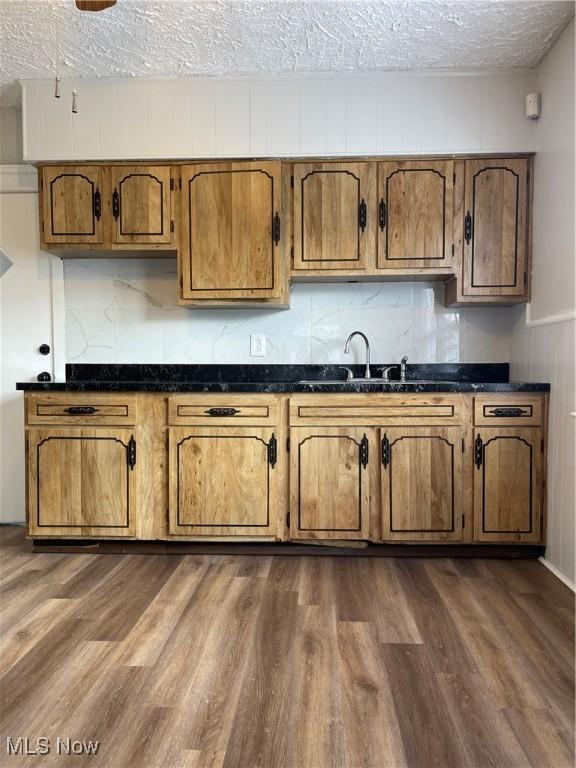 kitchen with dark hardwood / wood-style floors, sink, a textured ceiling, and decorative backsplash