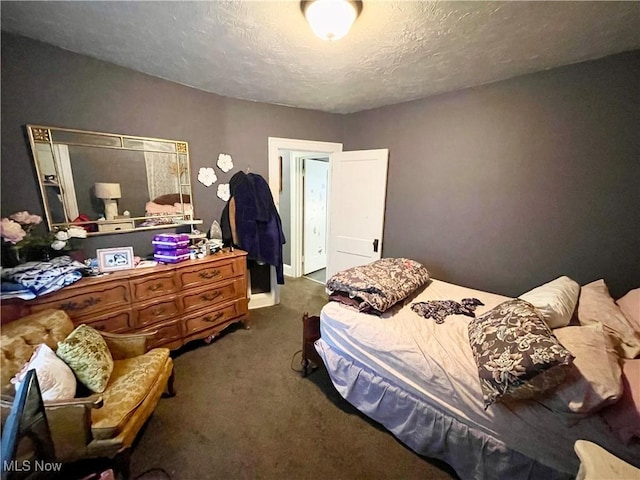 bedroom with a textured ceiling and dark colored carpet