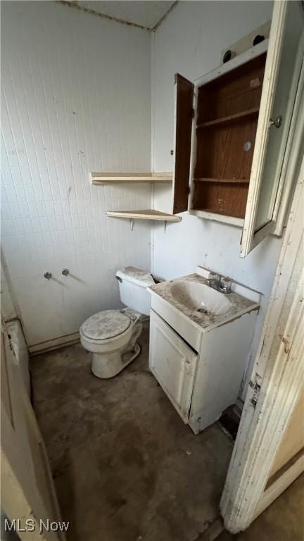 bathroom with vanity, toilet, and concrete floors