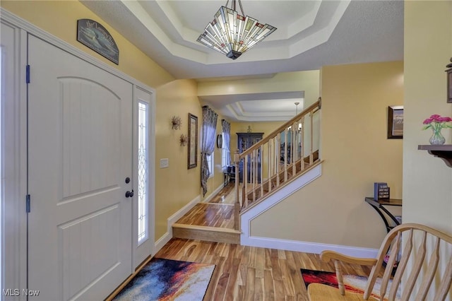 entrance foyer with a tray ceiling and light hardwood / wood-style flooring