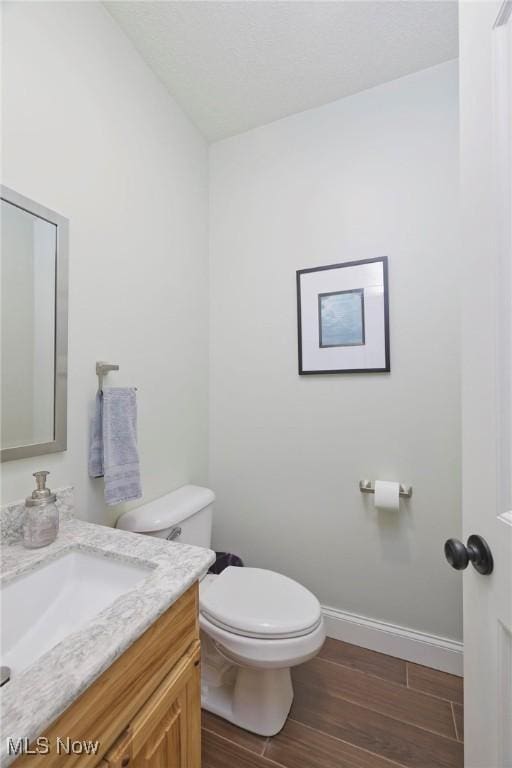 bathroom with hardwood / wood-style flooring, vanity, and toilet