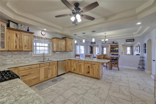 kitchen featuring sink, a tray ceiling, decorative light fixtures, stainless steel dishwasher, and tasteful backsplash