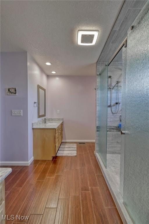 bathroom with a textured ceiling, a shower with shower door, and vanity