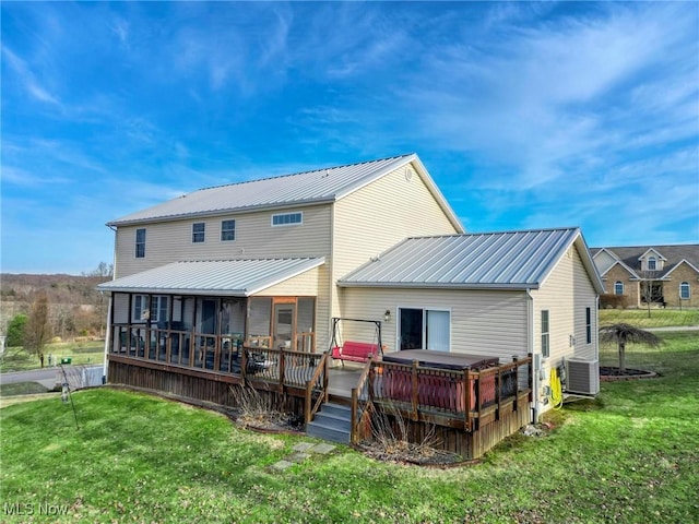 rear view of property with central AC unit, a lawn, a jacuzzi, a sunroom, and a wooden deck