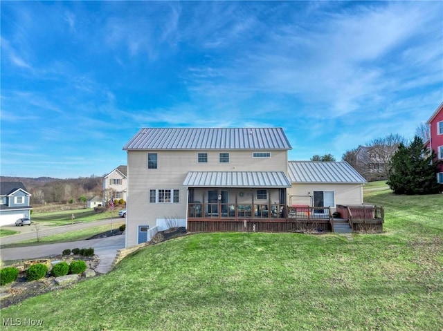 rear view of property with a deck, a sunroom, and a lawn