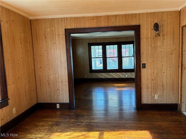 unfurnished room with dark wood-type flooring, crown molding, and wood walls